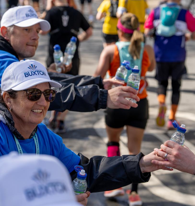 Volunteers hand out bottled water to runners over the barriers at the Brighton weekender