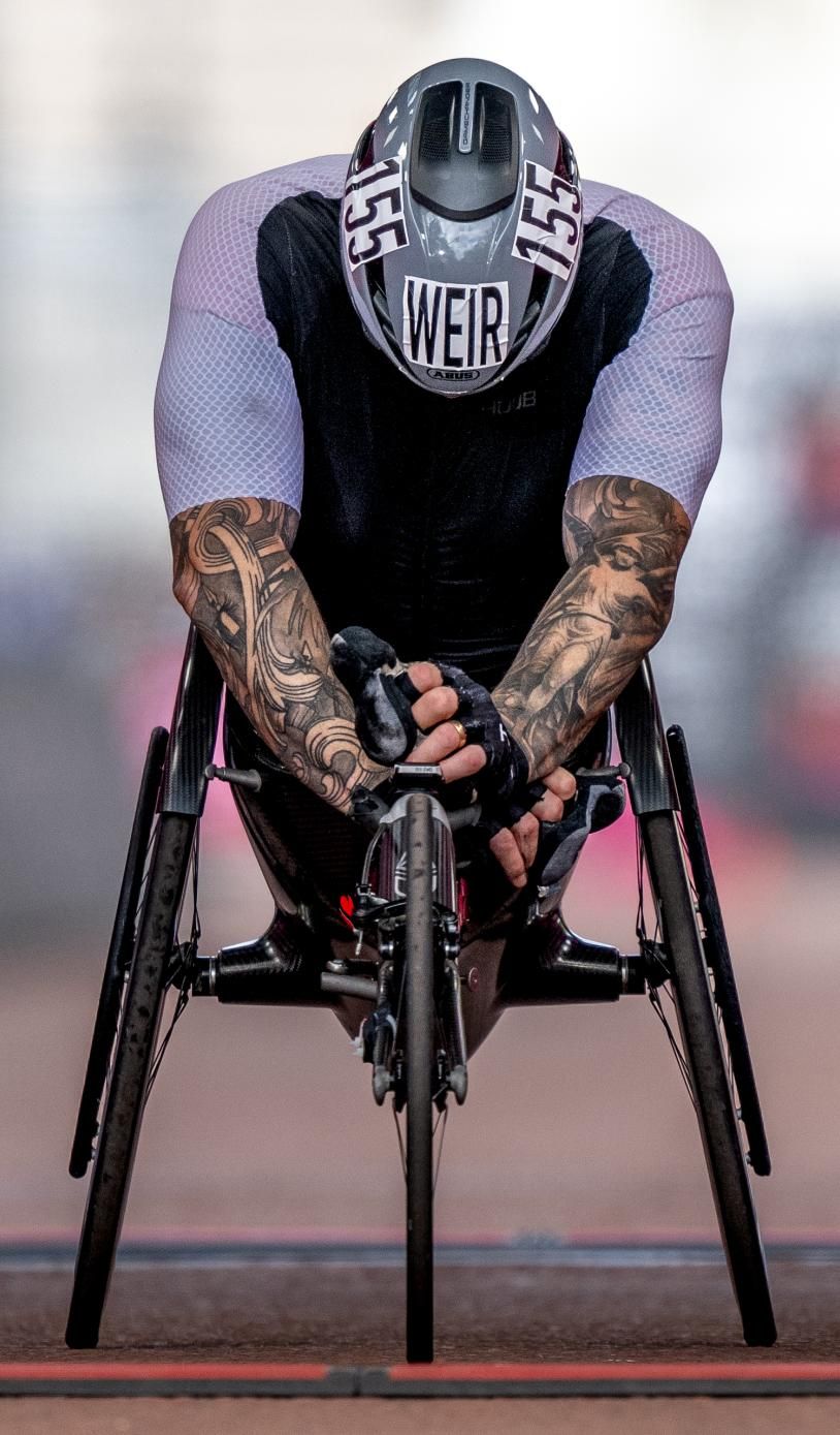 David Weir crossing the finish line lent over the front of his wheelchair
